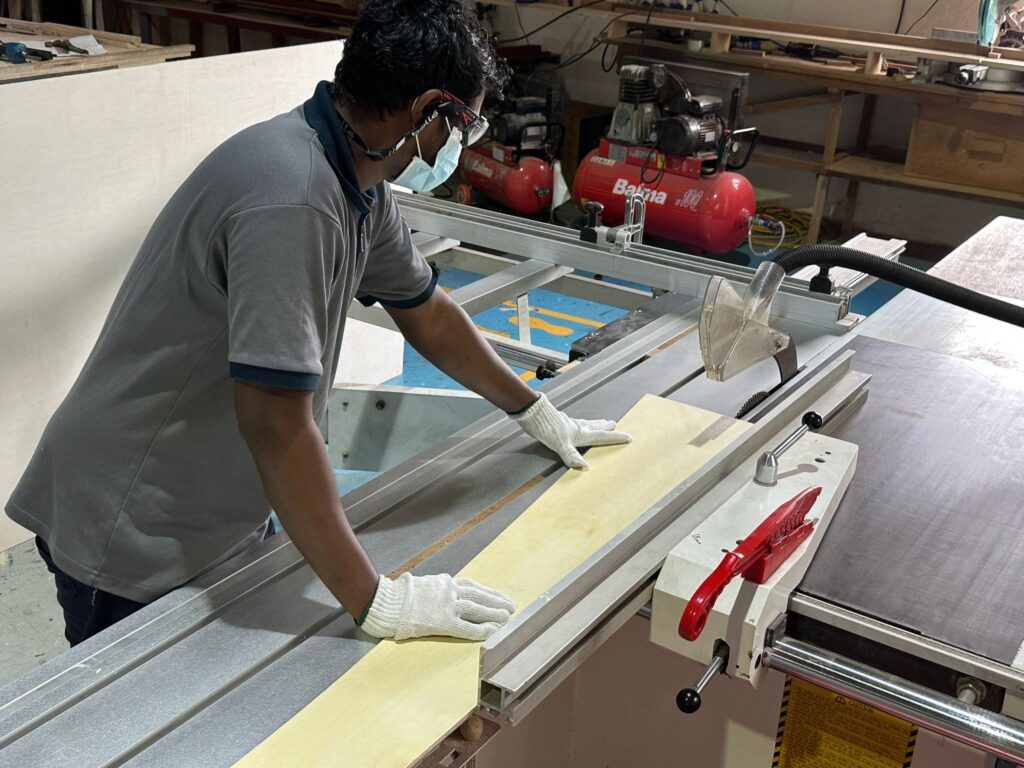 A worker wearing safety gear cutting a board to size